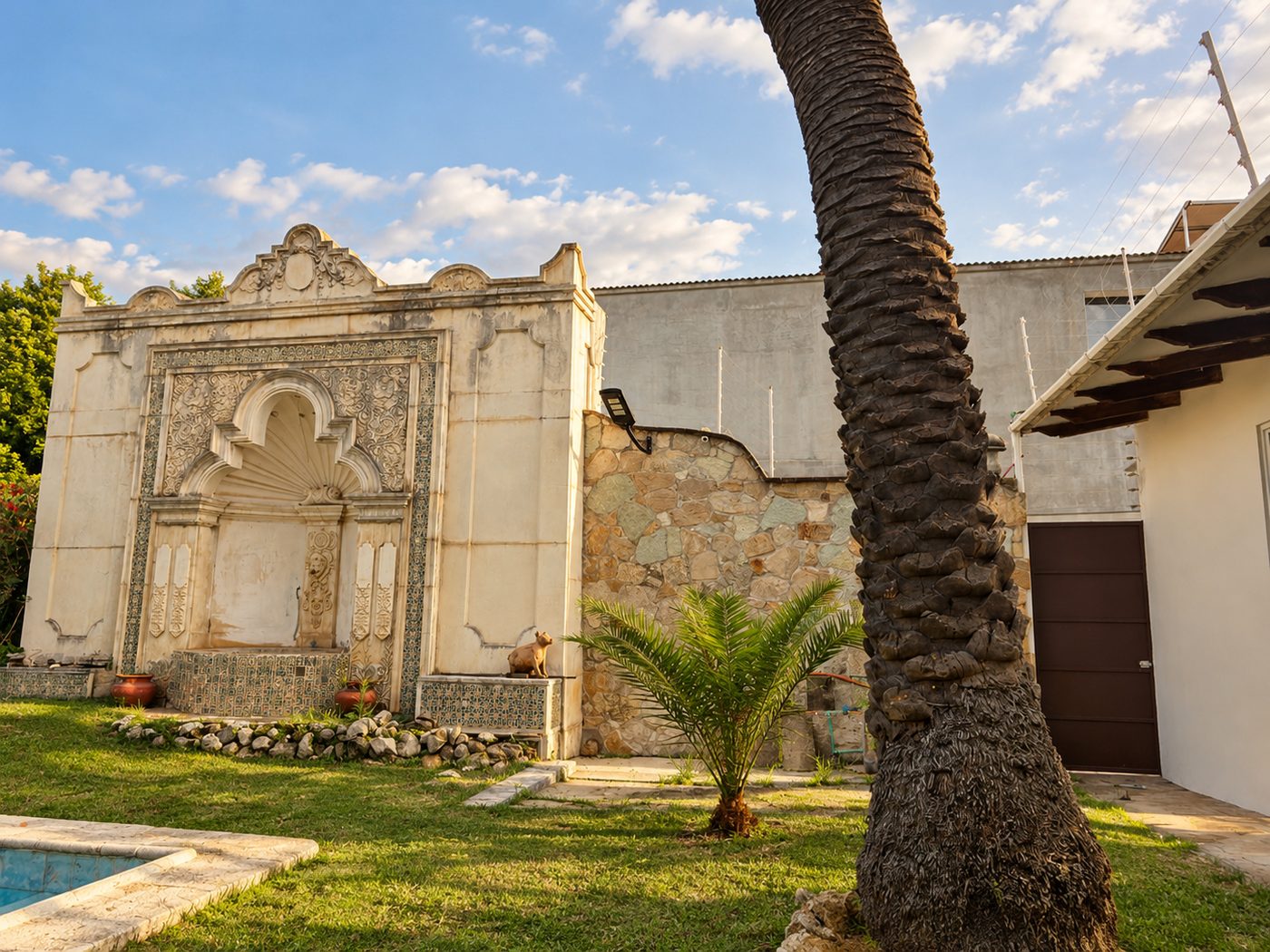 Jardín con fuente de azulejo, palmeras y alberca